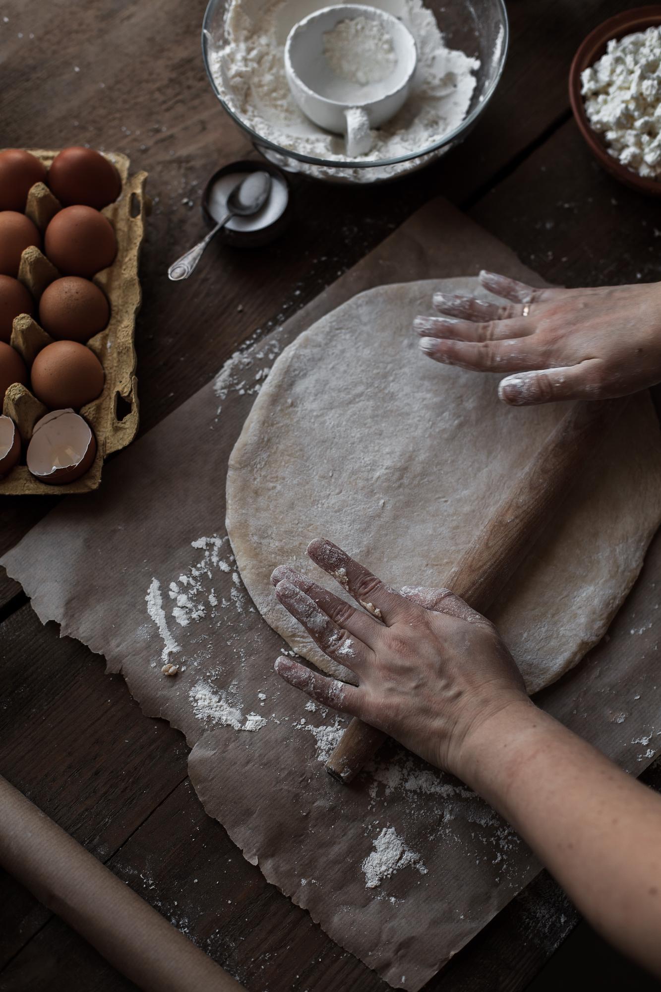 Hands preparing dough on wooden board